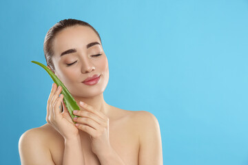 Wall Mural - Young woman with aloe vera leaf on light blue background. Space for text