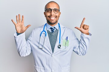 Wall Mural - Hispanic adult man wearing doctor uniform and stethoscope showing and pointing up with fingers number seven while smiling confident and happy.