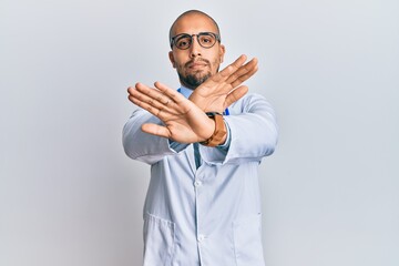 Poster - Hispanic adult man wearing doctor uniform and stethoscope rejection expression crossing arms and palms doing negative sign, angry face