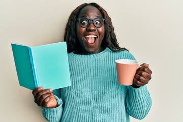 Poster - African young woman reading a book and drinking a cup of coffee celebrating crazy and amazed for success with open eyes screaming excited.