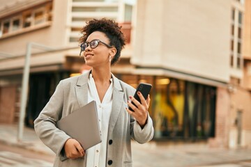 Canvas Print - Young african american businesswoman smiling happy using smartphone at the city.