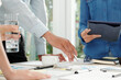 © DragonImages - Hands of financial analyst pointing at chart on table in meeting room when talking to marketing department managers