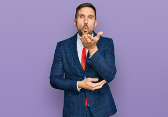 Poster - Handsome man with beard wearing business suit and tie looking at the camera blowing a kiss with hand on air being lovely and sexy. love expression.