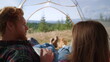 © stockbusters - Young couple relaxing in camping tent. Serious woman and man talking together