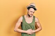 © Krakenimages.com - Young hispanic man wearing summer hat with hand on stomach because indigestion, painful illness feeling unwell. ache concept.