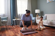 © Seventyfour - Full length portrait of African-American woman unrolling yoga mat for home workout with little girl, copy space