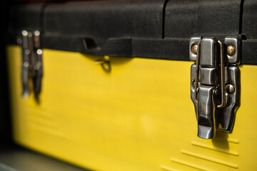 Yellow-black toolbox is closed with two metal locks. 