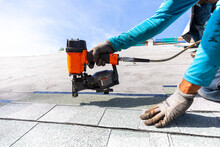 Roofer Installing Roof Shingles With Nail Gun
