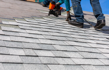 roofer installing roof shingles with nail gun