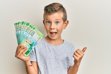 Wall Mural - Adorable caucasian kid holding russian 200 ruble banknotes pointing thumb up to the side smiling happy with open mouth