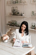 © Natalia - beautiful brunette in white shirt reading a magazine at a wooden table in a stylish room