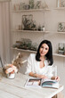 © Natalia - beautiful brunette in a white shirt and with a clock reading a magazine at the table
