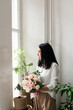 © Natalia - stylish brunette girl in a white shirt stands by the window with a bouquet of flowers in her hands
