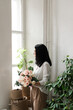 © Natalia - stylish brunette girl in a white shirt stands by the window with a bouquet of flowers in her hands