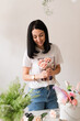© Natalia - brunette girl in white t-shirt collects a bouquet of flowers from roses florist at work