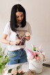 © Natalia - the florist collects a bouquet of flowers smiling brunette girl in a white t-shirt with flowers