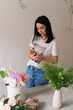 © Natalia - young girl brunette florist photographs a bouquet of flowers on the table on the phone