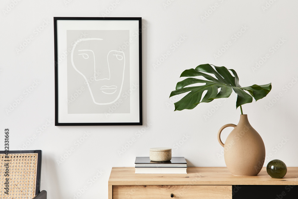 Stylish interior of living room with mock up poster frame, wooden commode, book, tropical leaf in ceramic vase and elegant personal accessories. Minimalist concept of home decor. Template. - obrazy, fototapety, plakaty 