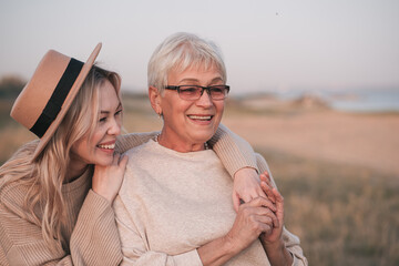 Adult daughter hugs her elderly mother in nature