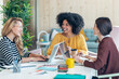 © nenetus - Casual multiethnic business women working with laptops while talking of they new projects together in coworking place.