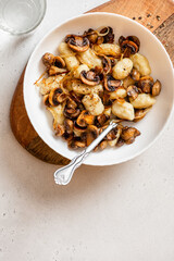 Wall Mural - Gnocchi with mushrooms. Cooked potato gnocchi with fried champignons and onions in a white plate on a light concrete table top view. Italian cuisine. Copy space for text.