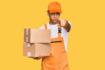 Canvas Print - Young handsome african american man holding delivery package pointing with finger to the camera and to you, confident gesture looking serious