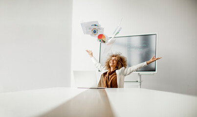 Wall Mural - African American businesswoman throwing paper in the air after receiving of great news in the modern office