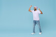 © ViDi Studio - Full length young overjoyed excited fun unshaven black african man in violet t-shirt hat glasses do winner gesture clench fist celebrate scream isolated on pastel blue background studio portrait