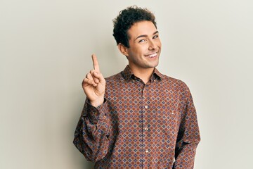 Poster - Handsome hispanic man wearing casual clothes showing and pointing up with finger number one while smiling confident and happy.