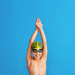 portrait of a sporty boy in a swimming cap, glasses and a bathing suit, performing exercises on a blue background. child enjoys swimming in a sports school. concept healthy lifestyle and sports.