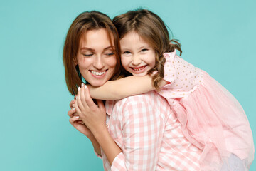 Happy woman in pink clothes have fun with child baby girl 5-6 years old Mommy little kid daughter stand behind hug kiss isolated on pastel blue azure background studio Mothers Day love family concept