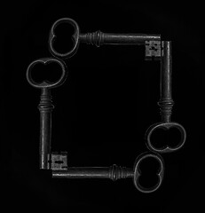 Wall Mural - frame made from four Old metal keys isolated on black background.