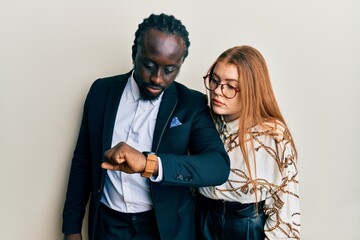 Sticker - Young interracial couple wearing business and elegant clothes checking the time on wrist watch, relaxed and confident