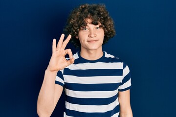 Handsome young man wearing casual striped t shirt smiling positive doing ok sign with hand and fingers. successful expression.