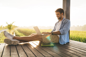 Happy man with laptop working remotely on terrace