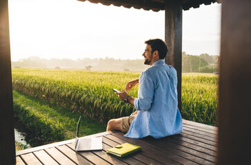 positive man working remotely with gadgets in countryside