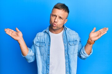 Poster - Handsome muscle man wearing casual denim jacket clueless and confused with open arms, no idea and doubtful face.