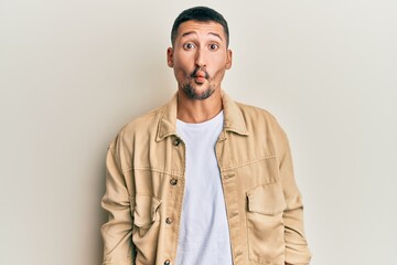 Wall Mural - Handsome man with tattoos wearing casual brown denim jacket making fish face with lips, crazy and comical gesture. funny expression.