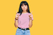 © Krakenimages.com - Young hispanic girl wearing casual clothes pointing up looking sad and upset, indicating direction with fingers, unhappy and depressed.