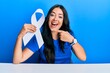 © Krakenimages.com - Beautiful brunette young woman holding white ribbon smiling happy pointing with hand and finger