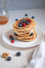 Wall Mural - Freshly cooked delicious pancakes with honey, walnut, raspberries and blueberries for breakfast.