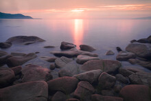 Many Stones In A Semicircle And Mountains In The Distance Under A Pink Sunset And Purple Water On Baikal