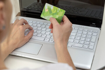 a girl with a Bank card in her hands in front of a laptop