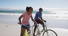 African American Couple Smiling And Riding Bikes On The Beach