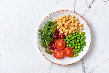 Wall Mural - A plate of healthy food: chickpeas with mix of fresh leaves, pomegranate, green peas and cherry tomatoes