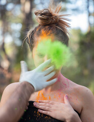 Young attractive woman at the Holi color festival of paints in park. Having fun outdoors. Multi Colored powder colors the face. Close Up portrait, people. Copy Space.