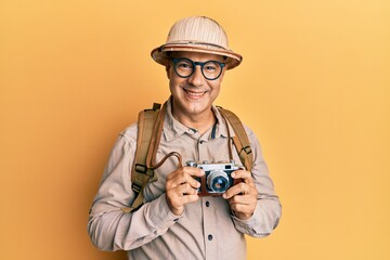 Wall Mural - Middle age bald man wearing explorer hat and vintage camera smiling with a happy and cool smile on face. showing teeth.