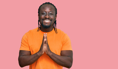 Sticker - Handsome young african american man wearing casual clothes praying with hands together asking for forgiveness smiling confident.