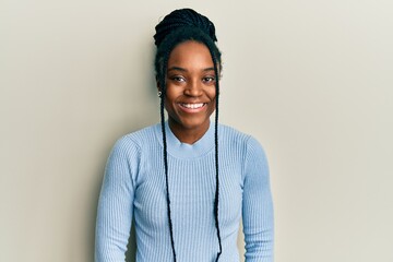 Wall Mural - African american woman with braided hair wearing casual blue sweater with a happy and cool smile on face. lucky person.