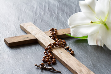 Wall Mural - Cross, rosary and white lily on black marble background. Passion and resurrection of Christ concept 